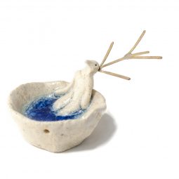 Hombre pájaro tumbado sobre cuenco de gres con fondo azul